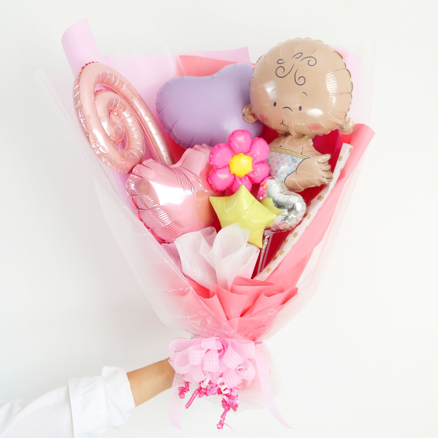 赤ちゃんをモチーフにしたピンク色メインのバルーンギフトを手に持った写真